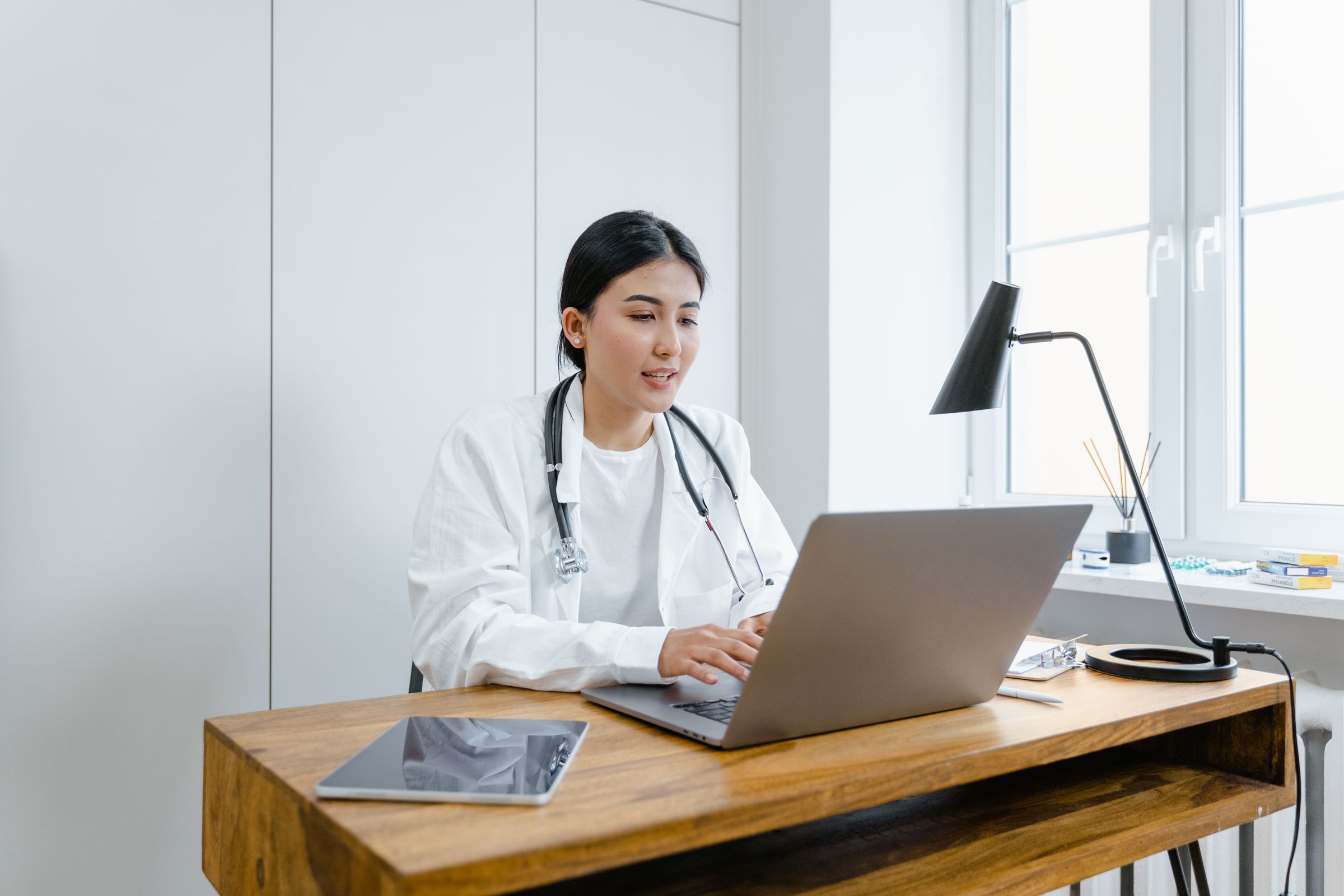 Physician reviewing patient records at a workstation in a modern medical practice.
